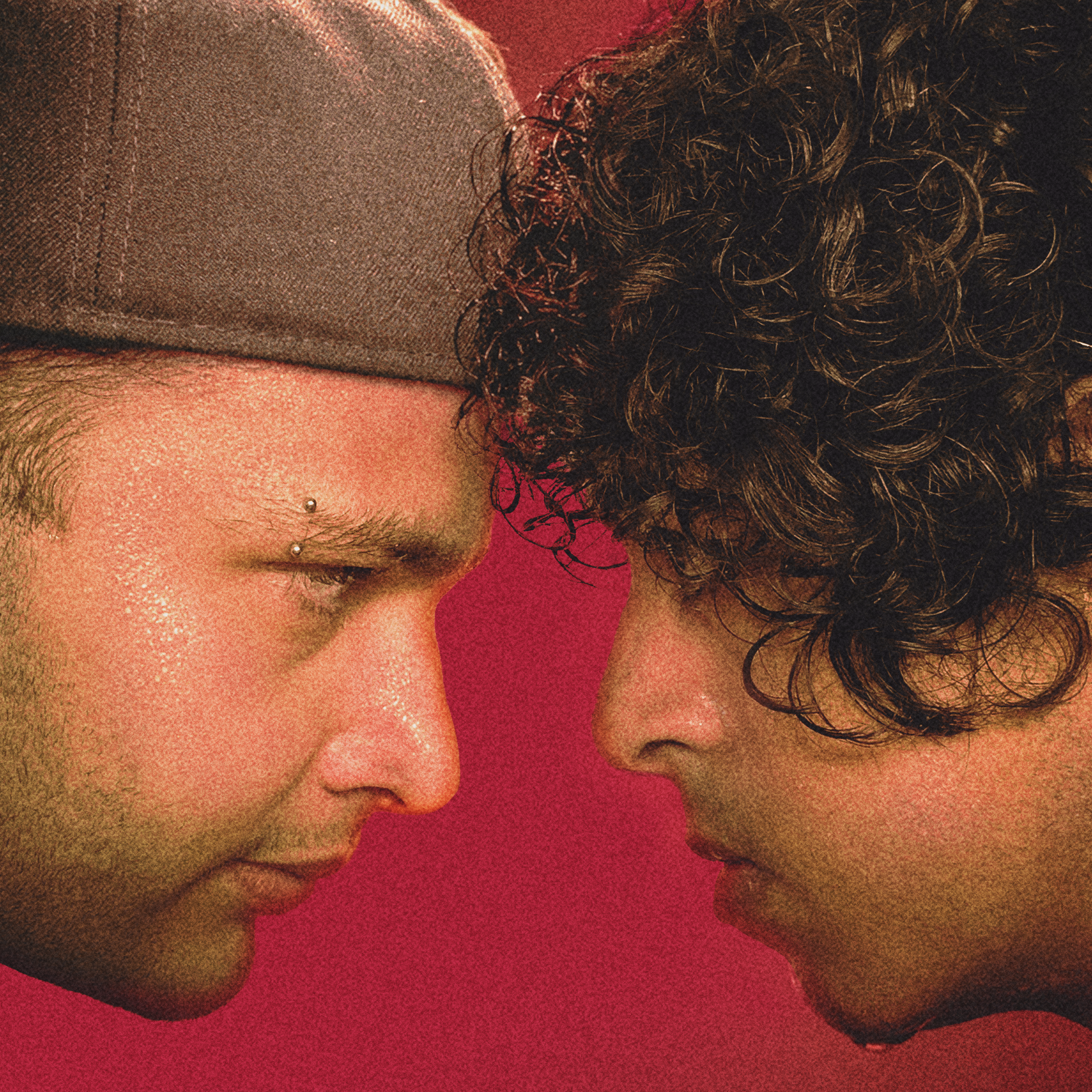 Cover artwork for Dente de Cão by Felipe Sanches and Eduardo Pavloski: closely framed faces turned toward each other, a deep red backdrop, and a pronounced grain texture.