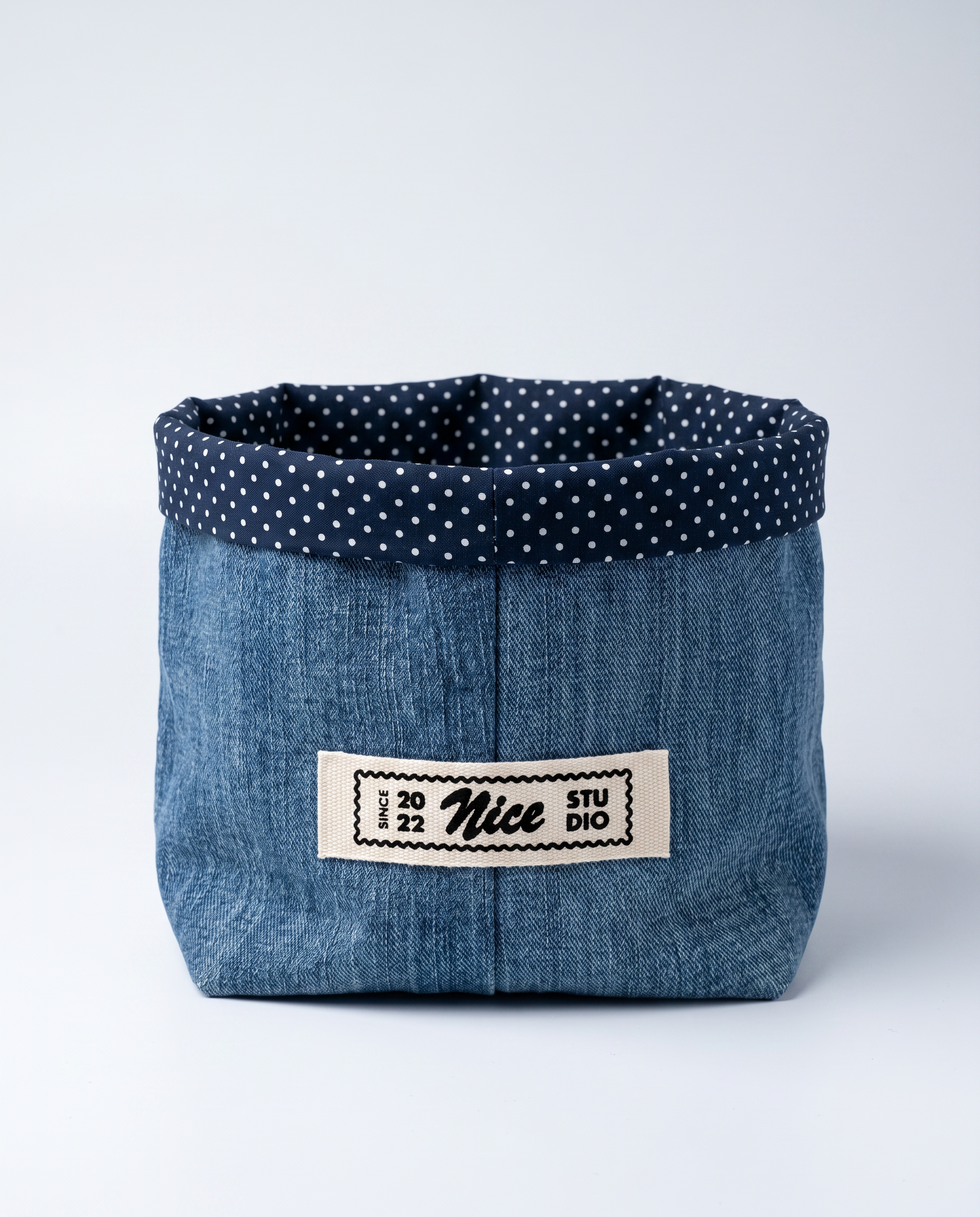 Front view of Nice Studio's denim cachepot, with a folded polka-dot lining and a sewn-on brand label.