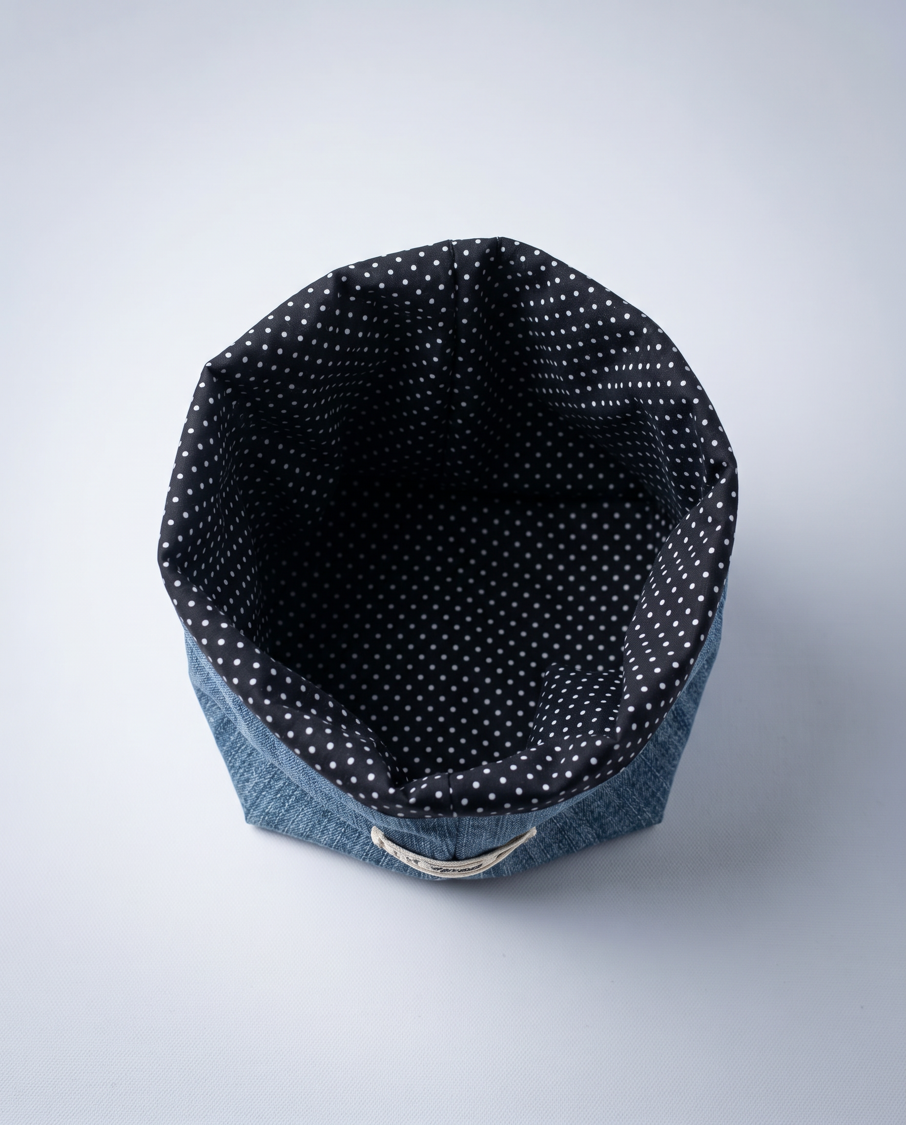 Overhead view of the Nice Studio cachepot, revealing its dark fabric lining patterned with small white polka dots.